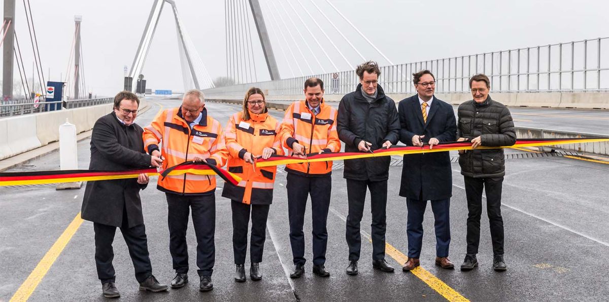 Eröffnung des 1. Teilstücks der neuen Rheinbrücke Leverkusen Foto: Durchschneiden des Bandes. Von Links nach rechts im Bild: Oliver Krischer (Minister für Naturschutz und Verkehr in Nordrhein Westfalen), Thomas Ganz (Leiter der Autobahn GmbH, Niederlassung Rheinland), Nicole Ritterbusch (Leiterin Rheinbrücken der Autobahn GmbH, Niederlassung Rheinland), Michael Güntner (Vorsitzender Geschäftsführer der Autobahn GmbH des Bundes), Hendrik Wüst (Ministerpräsident von Nordrhein-Westfalen), Oliver Luksic (Staatssekretär und Aufsichtsratsvorsitzender der Autobahn GmbH des Bundes) und Karl Lauterbach (Bundesgesundheitsminister und Bundestagsabgeordneter im Wahlkreis Leverkusen)